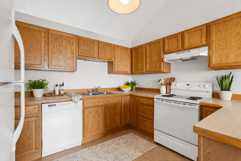 A kitchen with wooden cabinets and white appliances.
