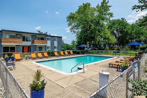 A pool area with a fence and a building in the background.