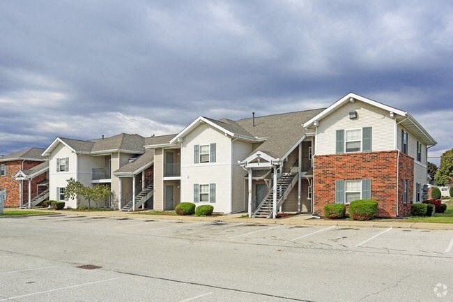 a row of apartment buildings in a parking lot with a cloudy sky in the background