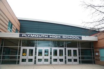 The front of Plymouth High School with a sign on the building.