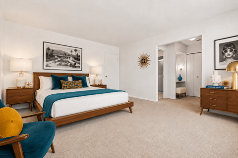 A bedroom with a bed, two nightstands, a chair, and a framed picture on the wall.
