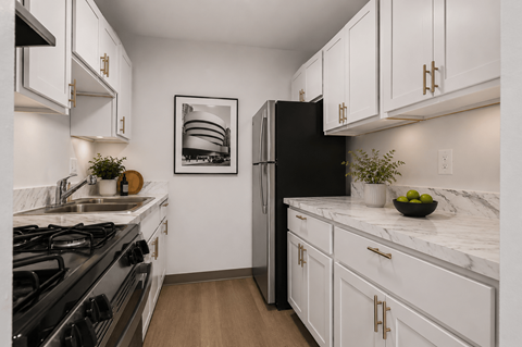 A modern kitchen with a black refrigerator and white cabinets.