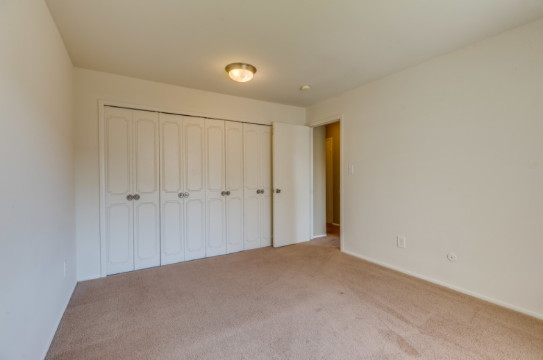 a bedroom with two closets and a carpeted floor