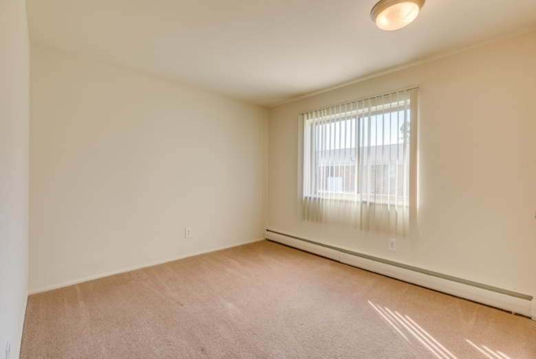 a spacious living room with a large window and carpeting