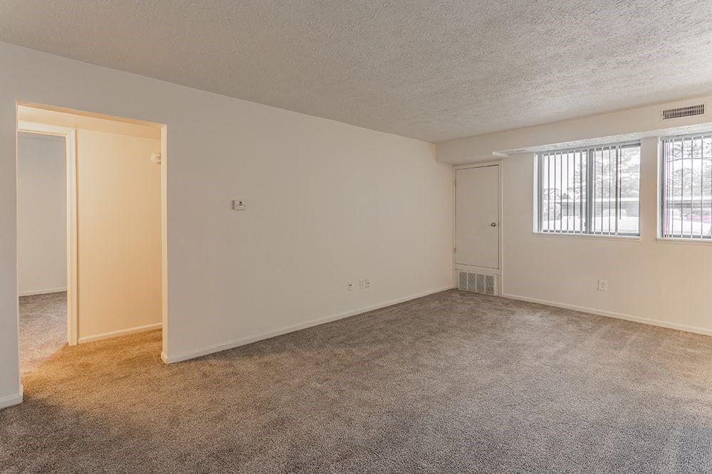 an empty living room with a door and a window