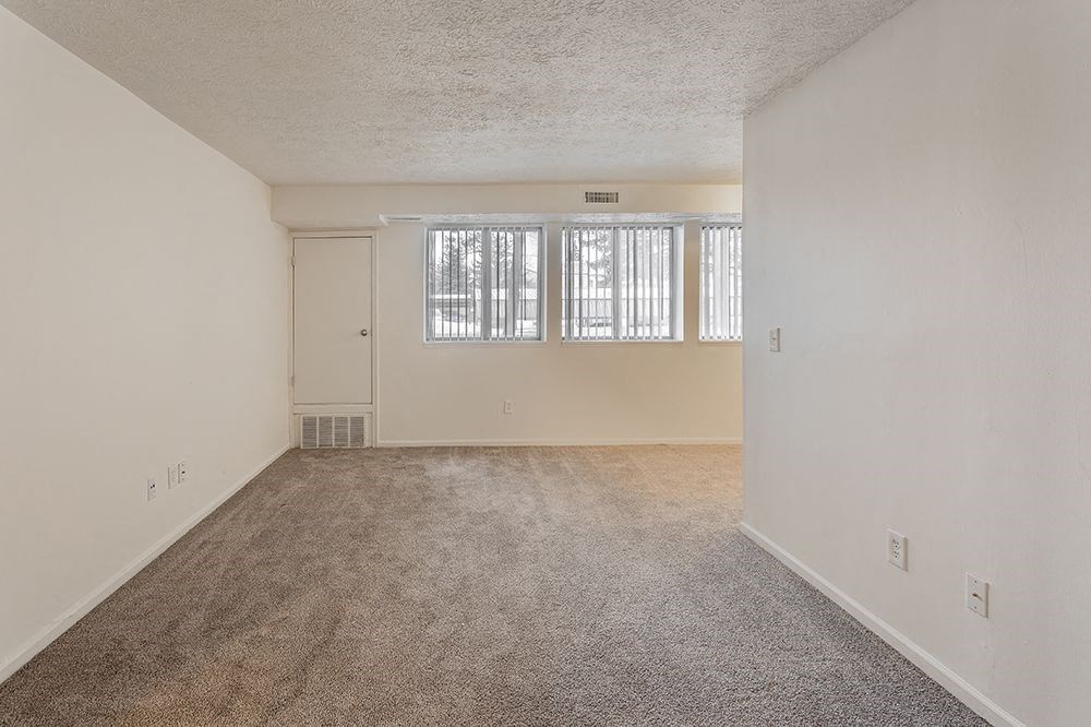 the living room and dining room of an empty home with carpet