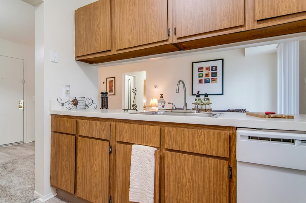 a kitchen with wooden cabinets and a sink and a white counter top