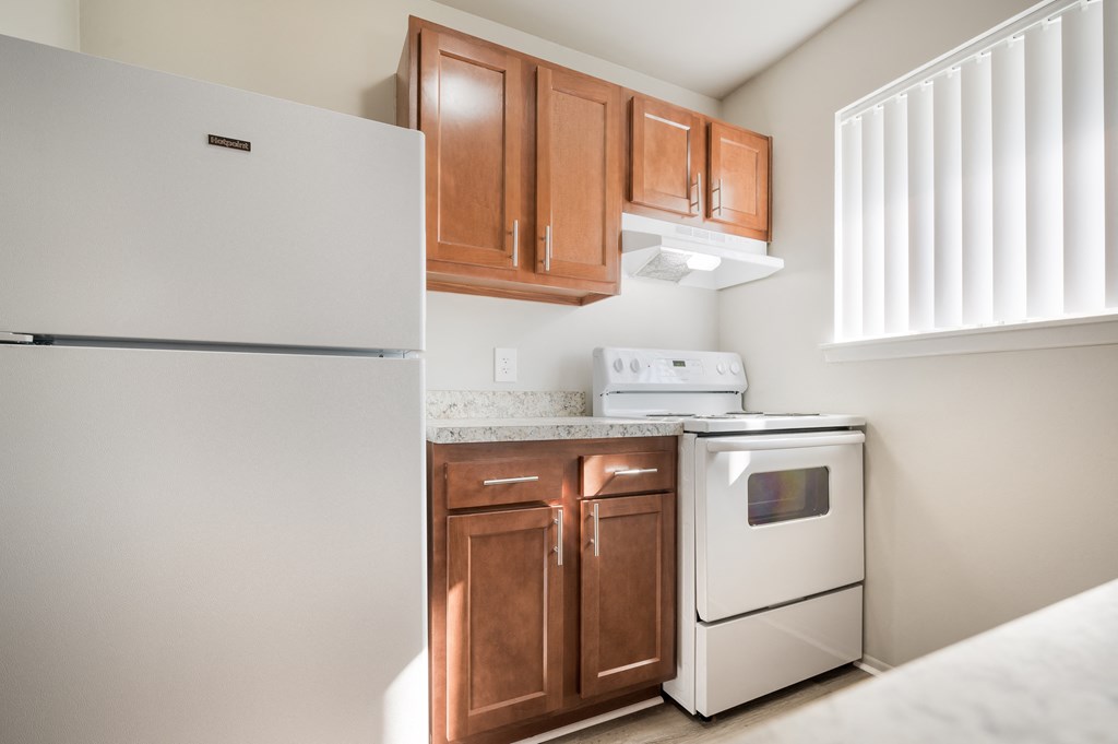 a kitchen with white appliances and wooden cabinets and a refrigerator