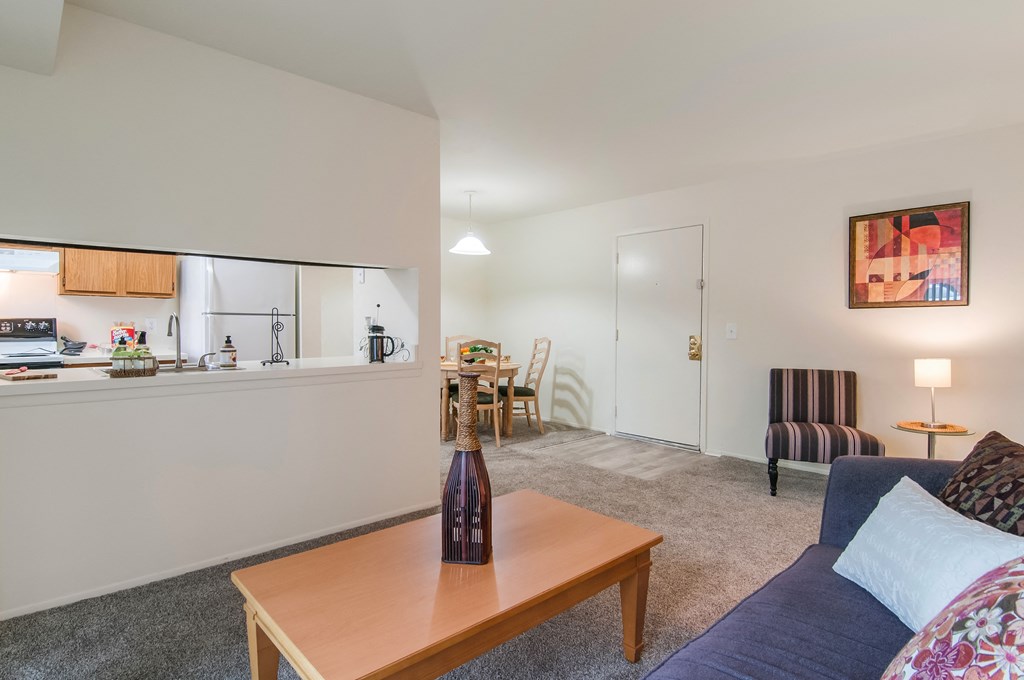 a living room with a couch and a coffee table and a kitchen