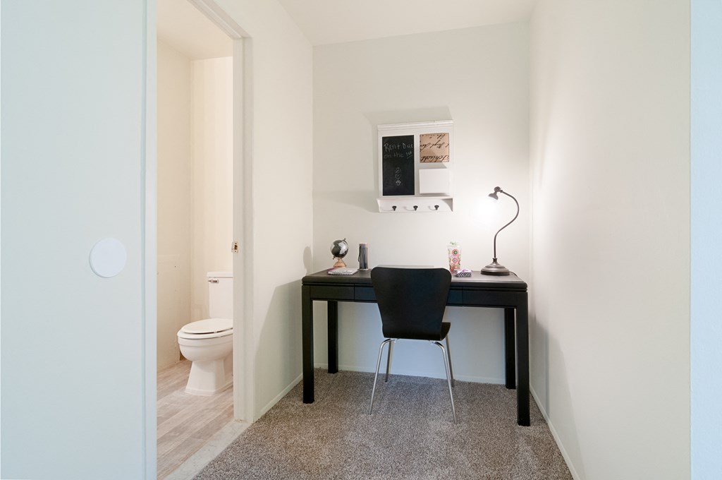 a desk with a chair in a room with a toilet