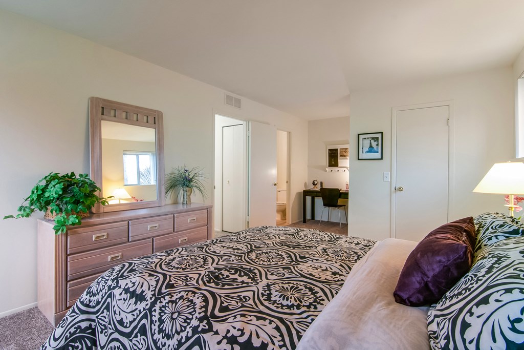 a bedroom with a bed and a dresser and a bathroom