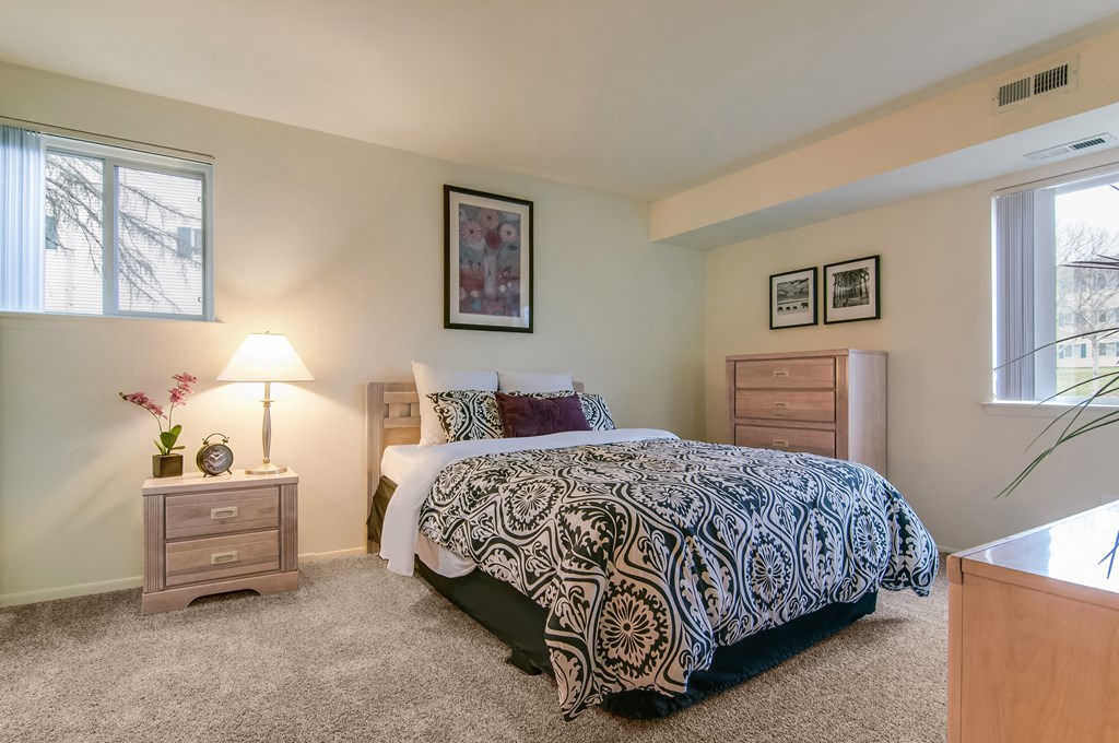 a bedroom with a bed and two dressers and a window