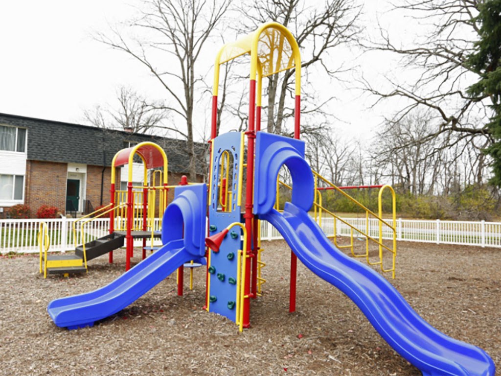 A playground with a blue slide and yellow and red structures.