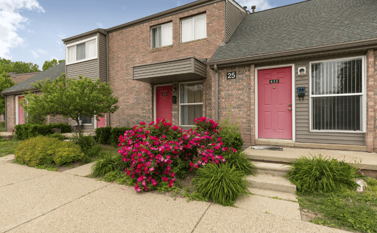 a pink door and pink flowers in front of a brick house