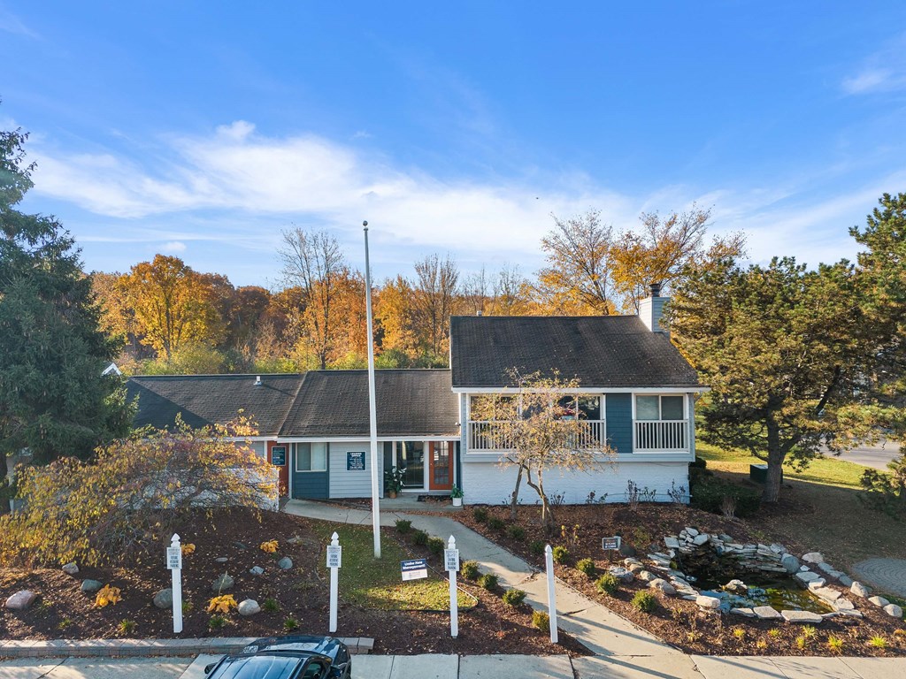 a white house with a gray roof and a yard with trees
