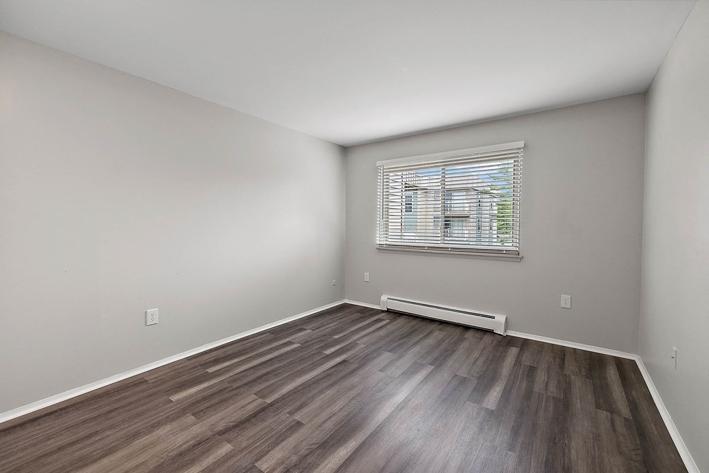 an empty room with wood floors and a window