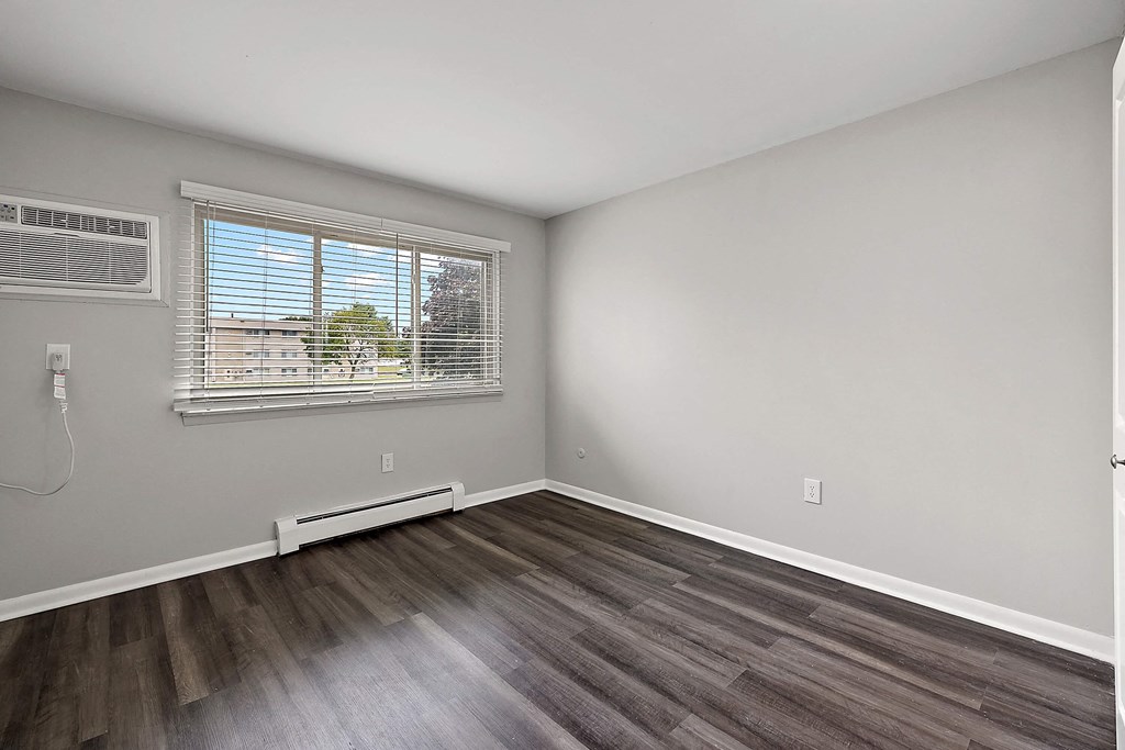 an empty living room with wood flooring and a window