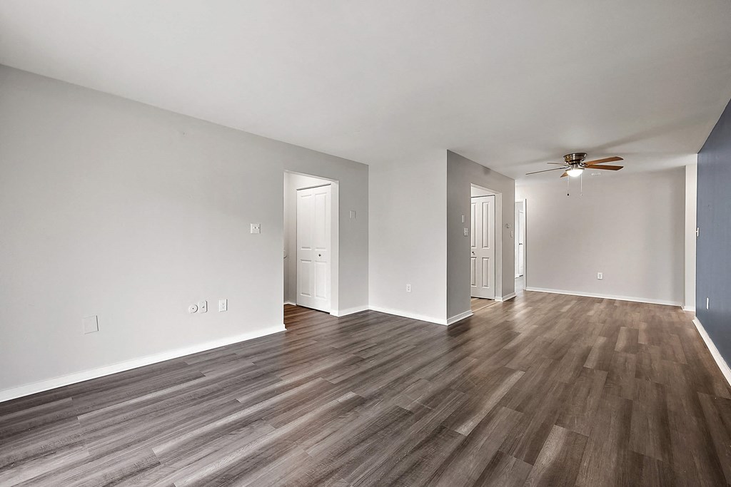 an empty living room with wood flooring and a ceiling fan