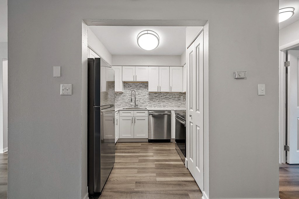 a kitchen with white cabinets and a stainless steel refrigerator