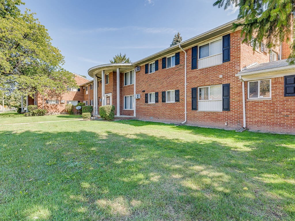 A red brick building with a green lawn in front.