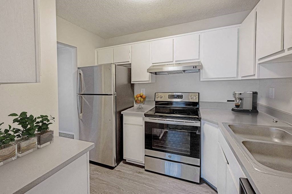 A kitchen with a stainless steel refrigerator, oven, and sink at The Waverly on the Lake - Belleville, MI Apartment , Belleville, Michigan