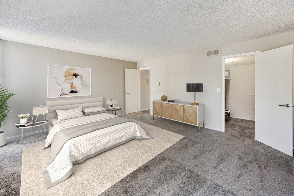A bedroom with a large bed and a bench. A bedroom with a large bed and a bench at The Waverly on the Lake - Belleville, MI Apartment , Belleville