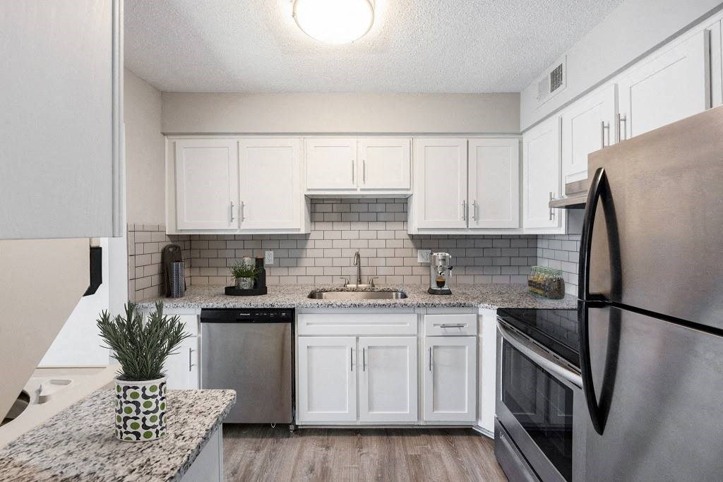 A kitchen with a black refrigerator and white cabinets. A kitchen with a black refrigerator and white cabinets at The Waverly on the Lake - Belleville, MI Apartment , Belleville, Michigan