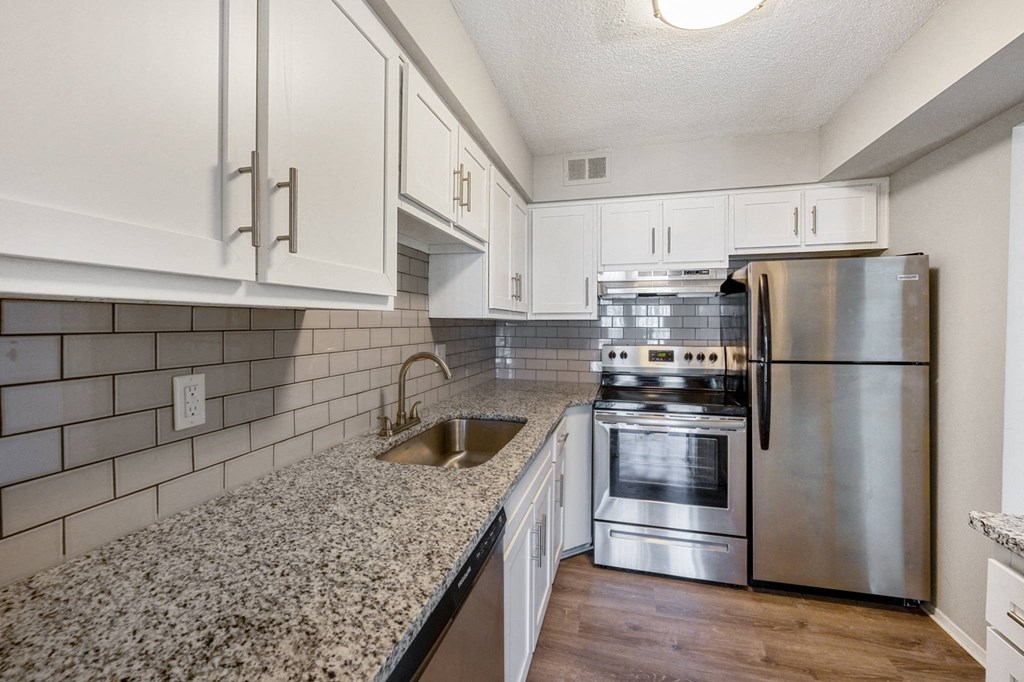 A kitchen with a stainless steel refrigerator, oven, and sink at The Waverly on the Lake - Belleville, MI Apartment , Michigan, 48111
