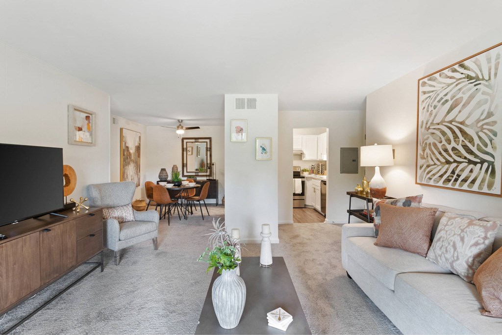 A living room with a grey couch and a wooden entertainment unit at The Waverly on the Lake - Belleville, MI Apartment , Michigan