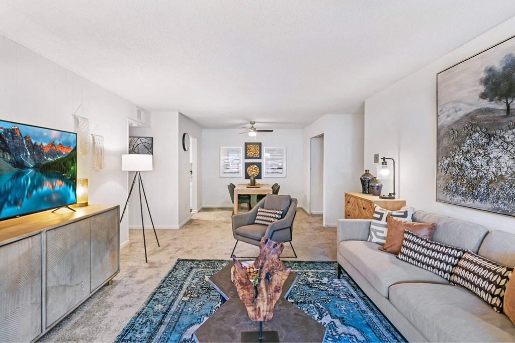 A living room with a couch, a chair, a coffee table, and a painting on the wall at The Waverly on the Lake - Belleville, MI Apartment , Michigan, 95050