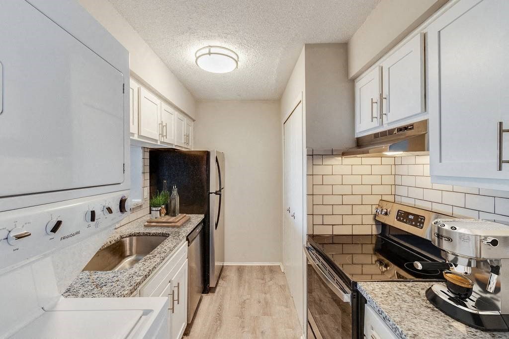 A kitchen with white cabinets and a black fridge at The Waverly on the Lake - Belleville, MI Apartment , Belleville, Michigan