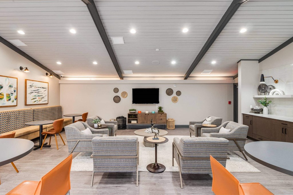 A modern living room with a grey sofa set, a coffee table, and a TV mounted on the wall at The Waverly on the Lake - Belleville, MI Apartment , Belleville