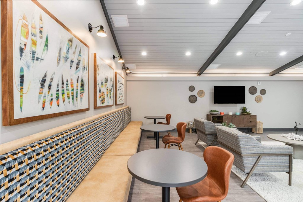 A room with a table, chairs and a wall of art at The Waverly on the Lake - Belleville, MI Apartment , Belleville, Michigan