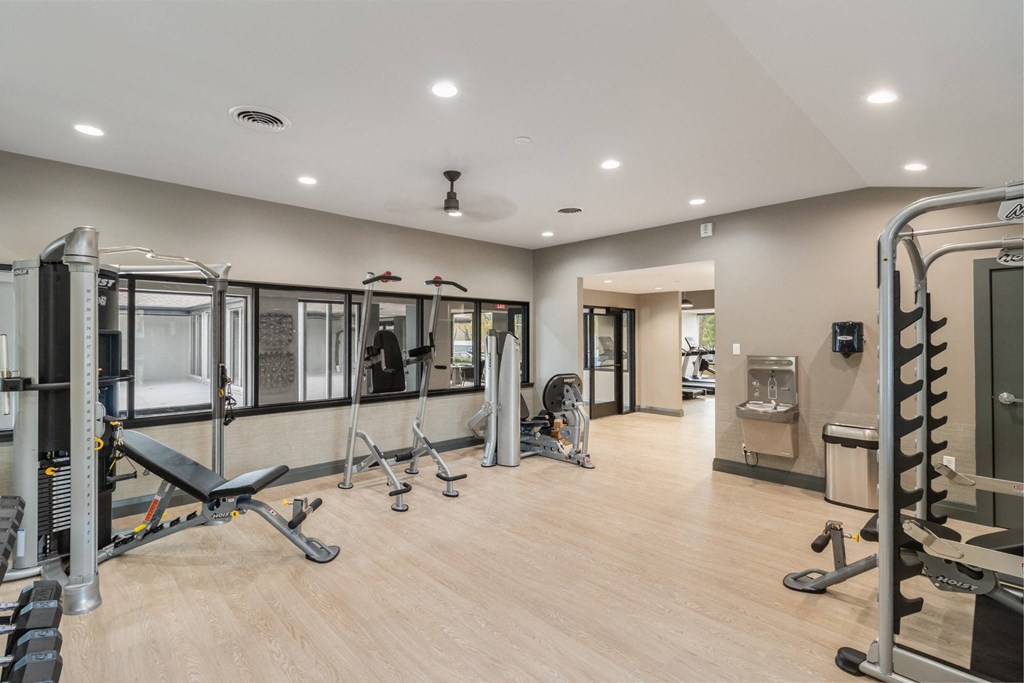 A spacious gym with a variety of equipment including treadmills, weights, and exercise machines at The Waverly on the Lake - Belleville, MI Apartment , Belleville, MI