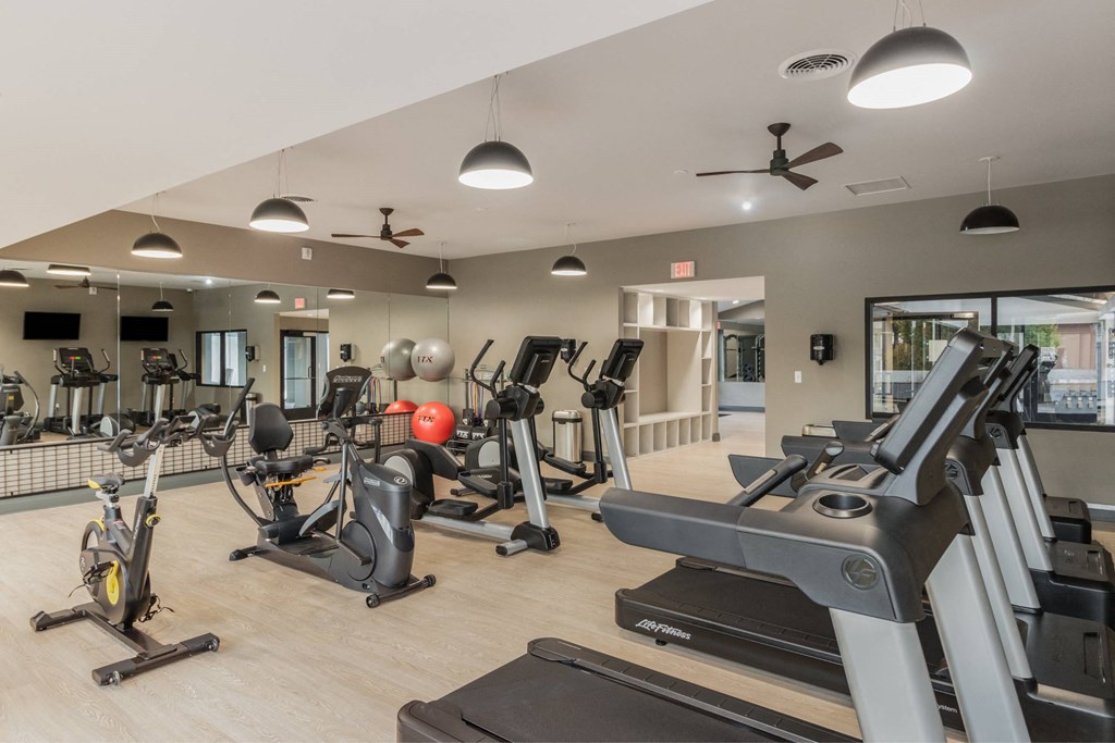 A gym with treadmills, elliptical machines, and other exercise equipment at The Waverly on the Lake - Belleville, MI Apartment , Michigan, 48111