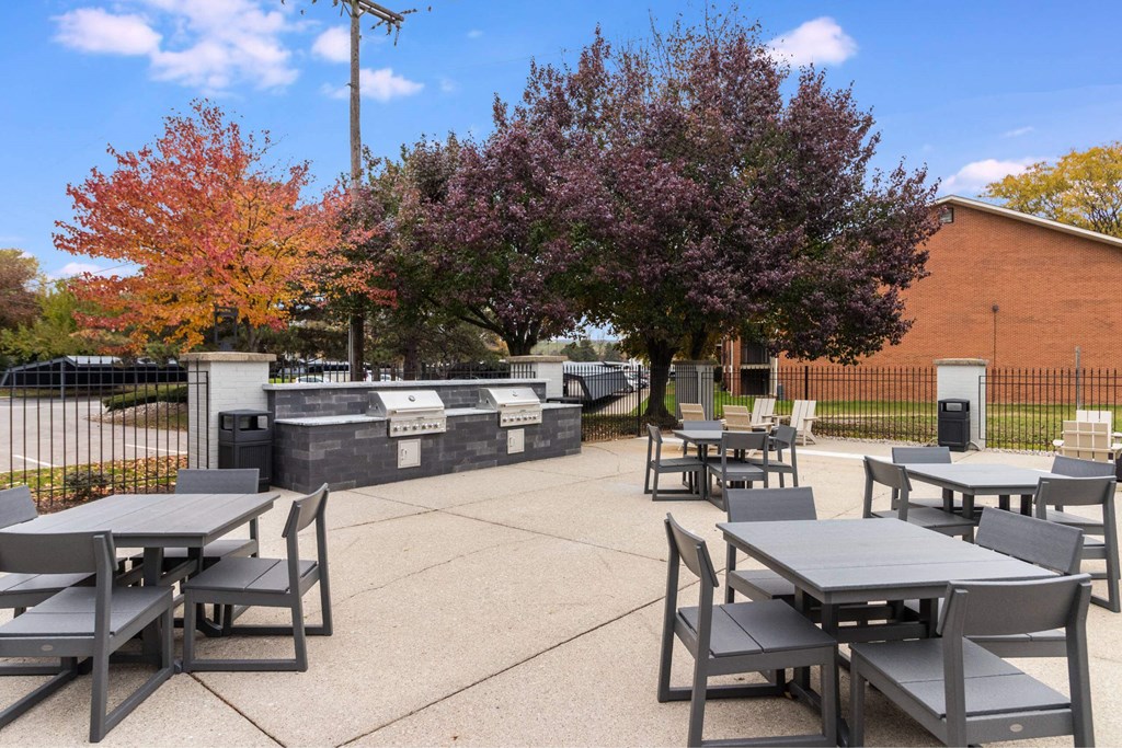 A park with tables and chairs surrounded by trees at The Waverly on the Lake - Belleville, MI Apartment , Michigan
