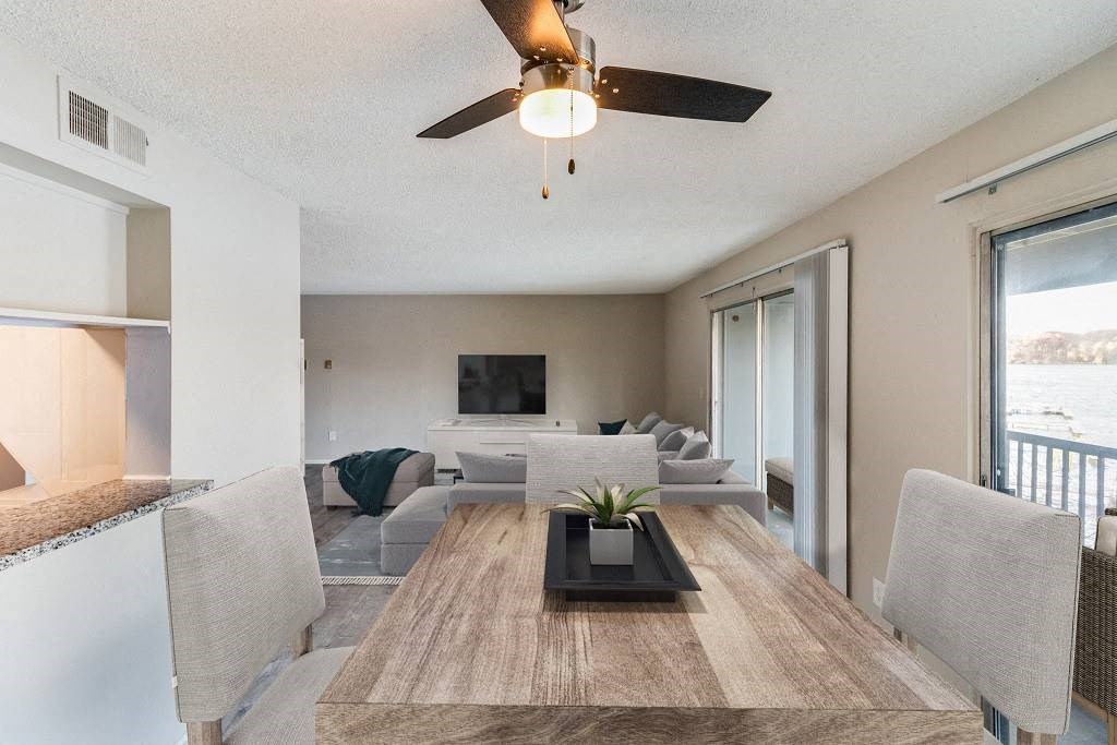 A modern dining room with a wooden table and grey chairs at The Waverly on the Lake - Belleville, MI Apartment , Belleville