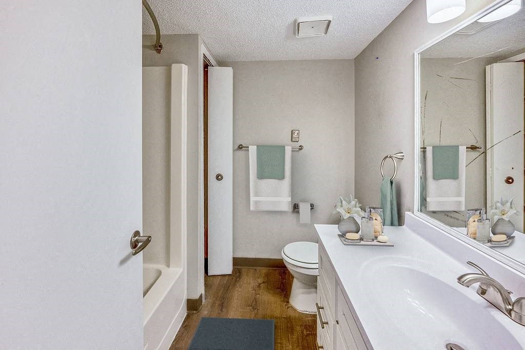 A white bathroom with a toilet, sink, and mirror at The Waverly on the Lake - Belleville, MI Apartment , Michigan