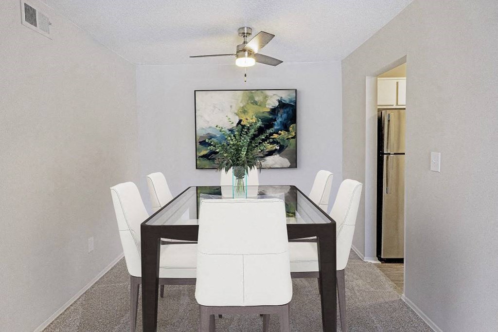 A dining room with a table and chairs and a painting on the wall at The Waverly on the Lake - Belleville, MI Apartment , Michigan, 48111