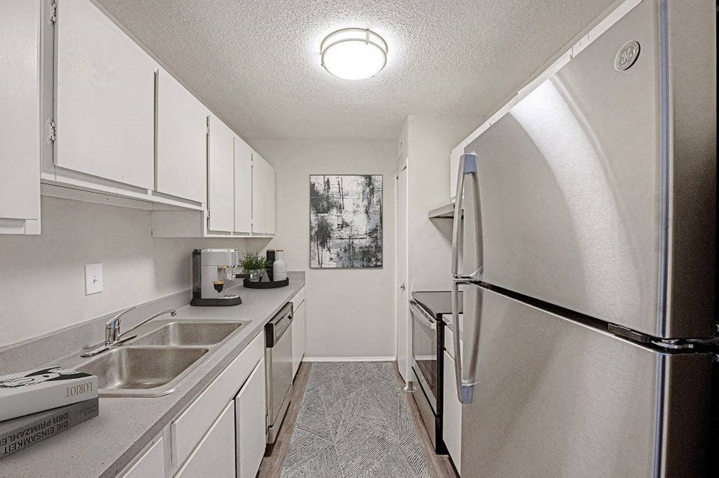 A kitchen with a sink, refrigerator, and cabinets at The Waverly on the Lake - Belleville, MI Apartment , Belleville, 48111