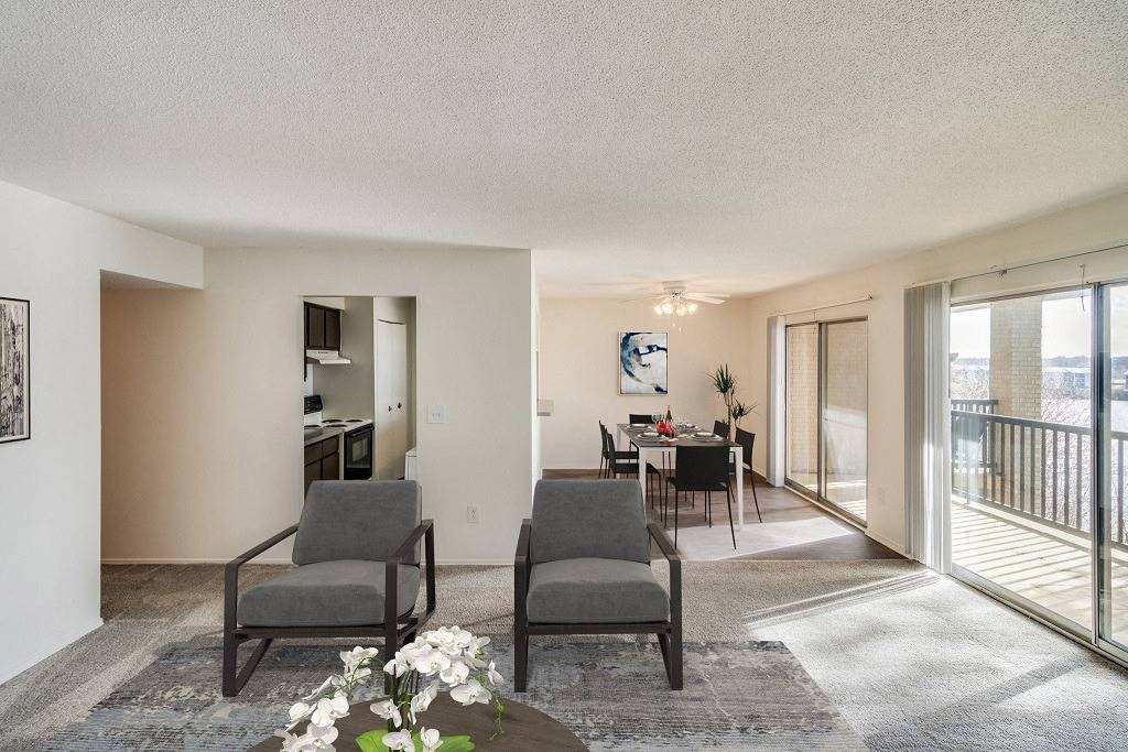 Two grey chairs are placed in a room with a table and a vase of flowers at The Waverly on the Lake - Belleville, MI Apartment , Belleville, Michigan