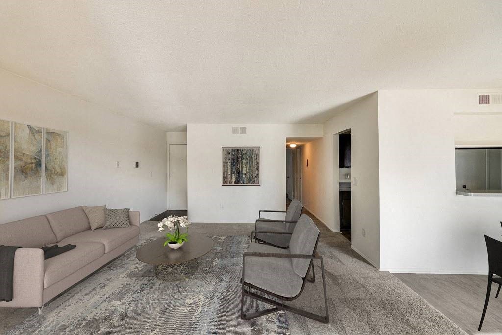 A living room with a grey couch, a coffee table, and a painting on the wall at The Waverly on the Lake - Belleville, MI Apartment , Belleville