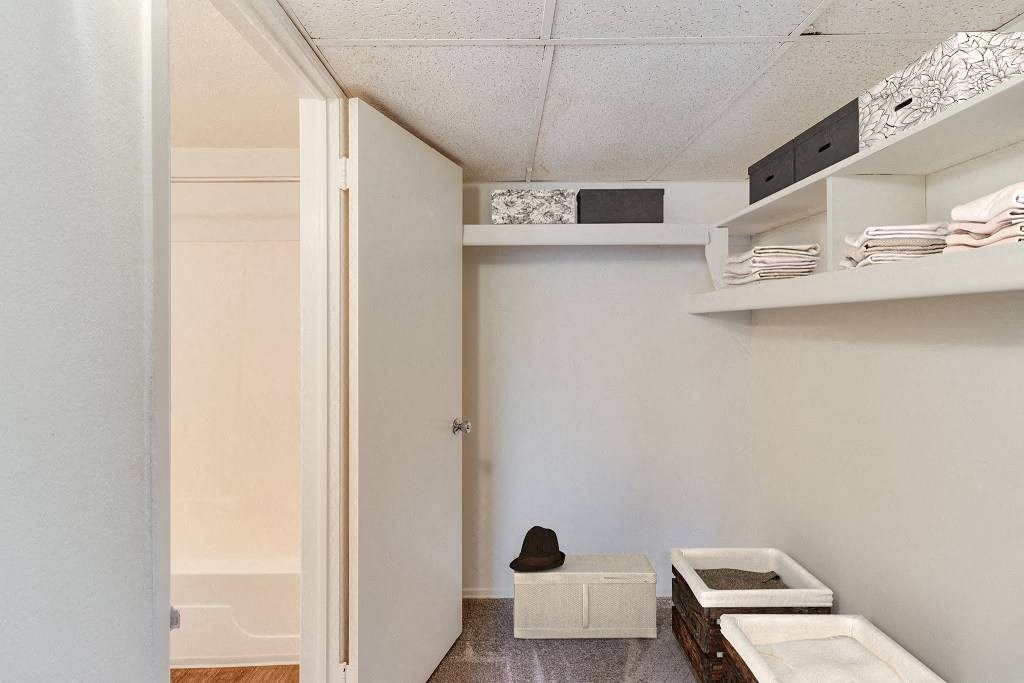 A small room with a white door and a white bench with a black hat on it at The Waverly on the Lake - Belleville, MI Apartment, Belleville, MI, 48111