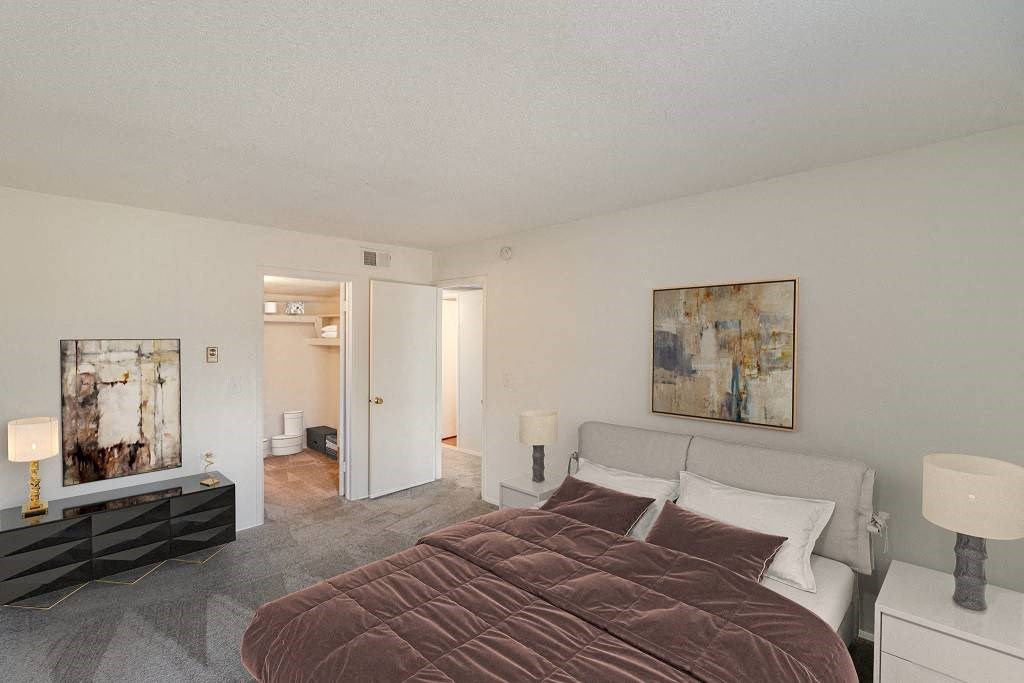 A bedroom with a large bed and a painting on the wall at The Waverly on the Lake - Belleville, MI Apartment , Belleville, Michigan