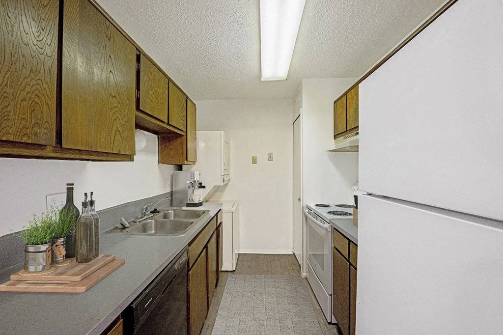 A kitchen with wooden cabinets and a white refrigerator at The Waverly on the Lake - Belleville, MI Apartment , Belleville, Michigan