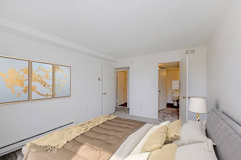 A bedroom with a bed, a lamp, and a map on the wall at The Waverly on the Lake - Belleville, MI Apartment , Belleville
