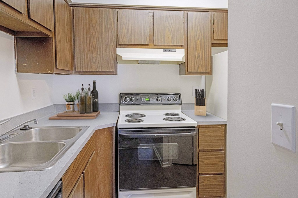 A modern kitchen with wooden cabinets and stainless steel appliances at The Waverly on the Lake - Belleville, MI Apartment, Belleville, MI, 95050