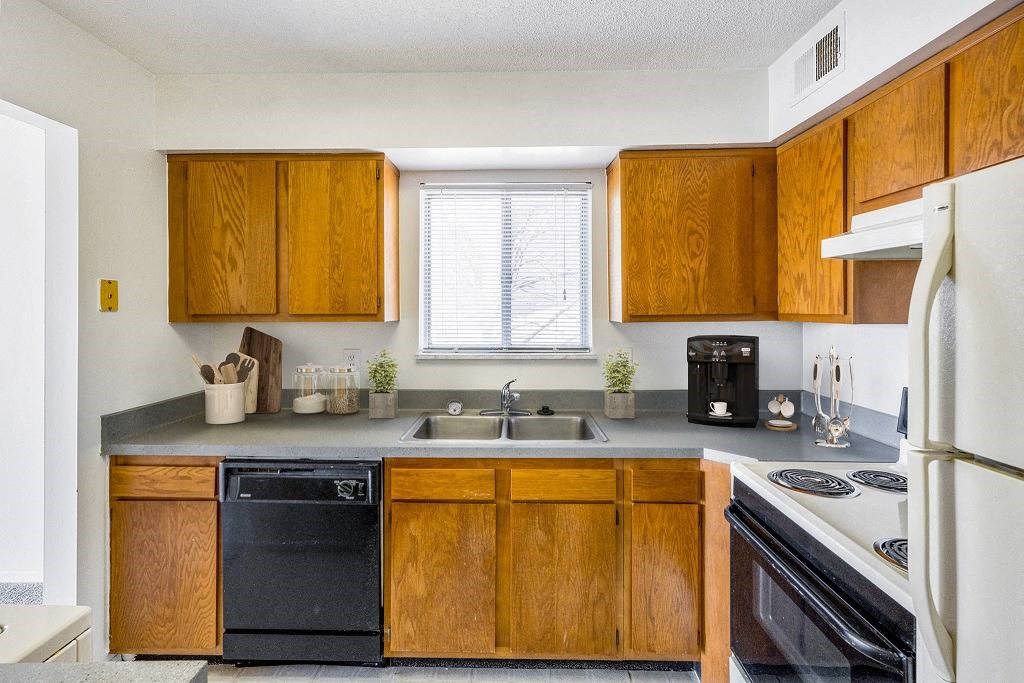 A kitchen with wooden cabinets and a black dishwasher at The Waverly on the Lake - Belleville, MI Apartment , Belleville