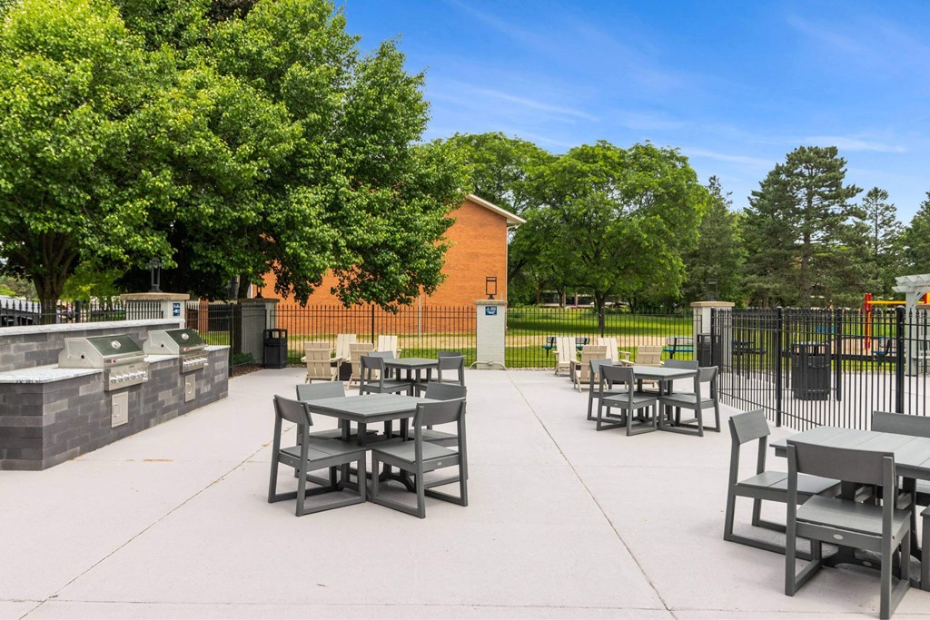 A park with tables and chairs and a fence at The Waverly on the Lake - Belleville, MI Apartment, Belleville, MI, 95050