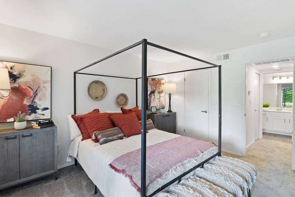 A bedroom with a four poster bed and a grey cabinet at The Waverly on the Lake - Belleville, MI Apartment , Belleville, Michigan